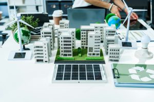 A miniature city model on a desk sustainable technology, with wind turbines and solar panels.