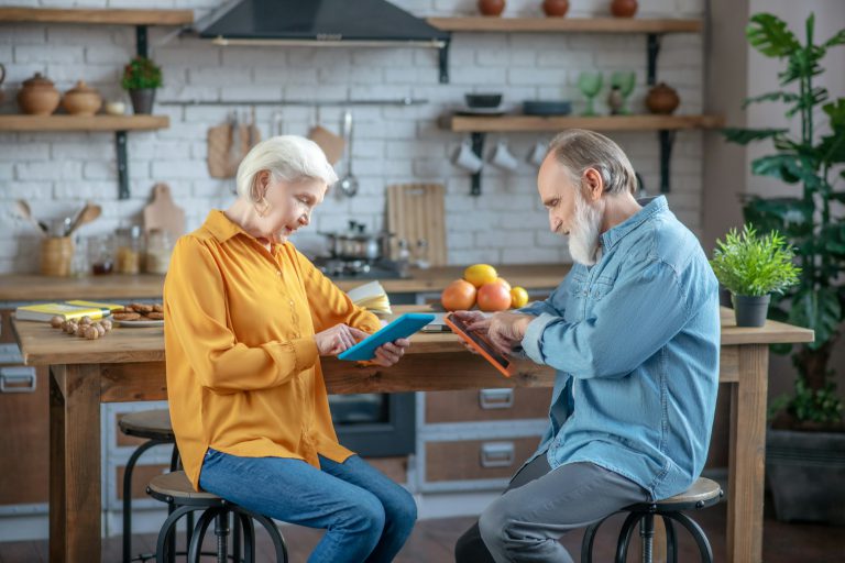 Elderly man and woman using tablets for surfing internet